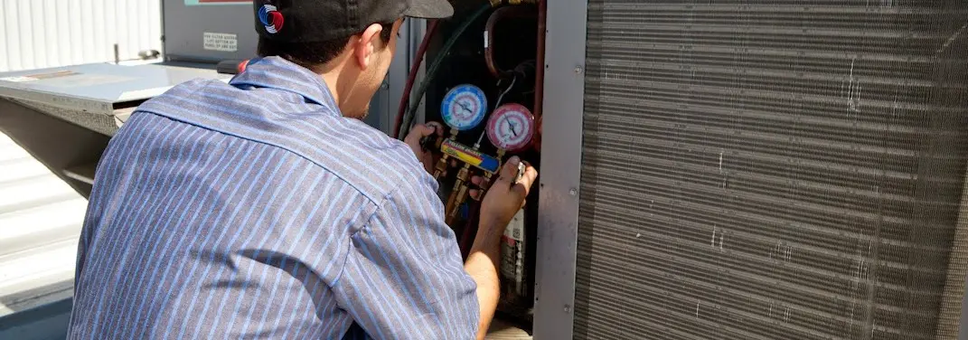 HVAC technician servicing a condenser unit in Douglas